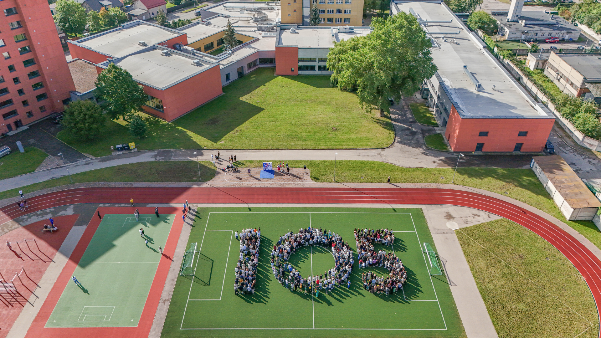 Skolēni sastājušies sporta laukumā skaitlī "105"