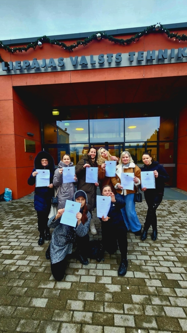 Kopbilde ar dalībniekiem — ar diplomiem skolas priekšā