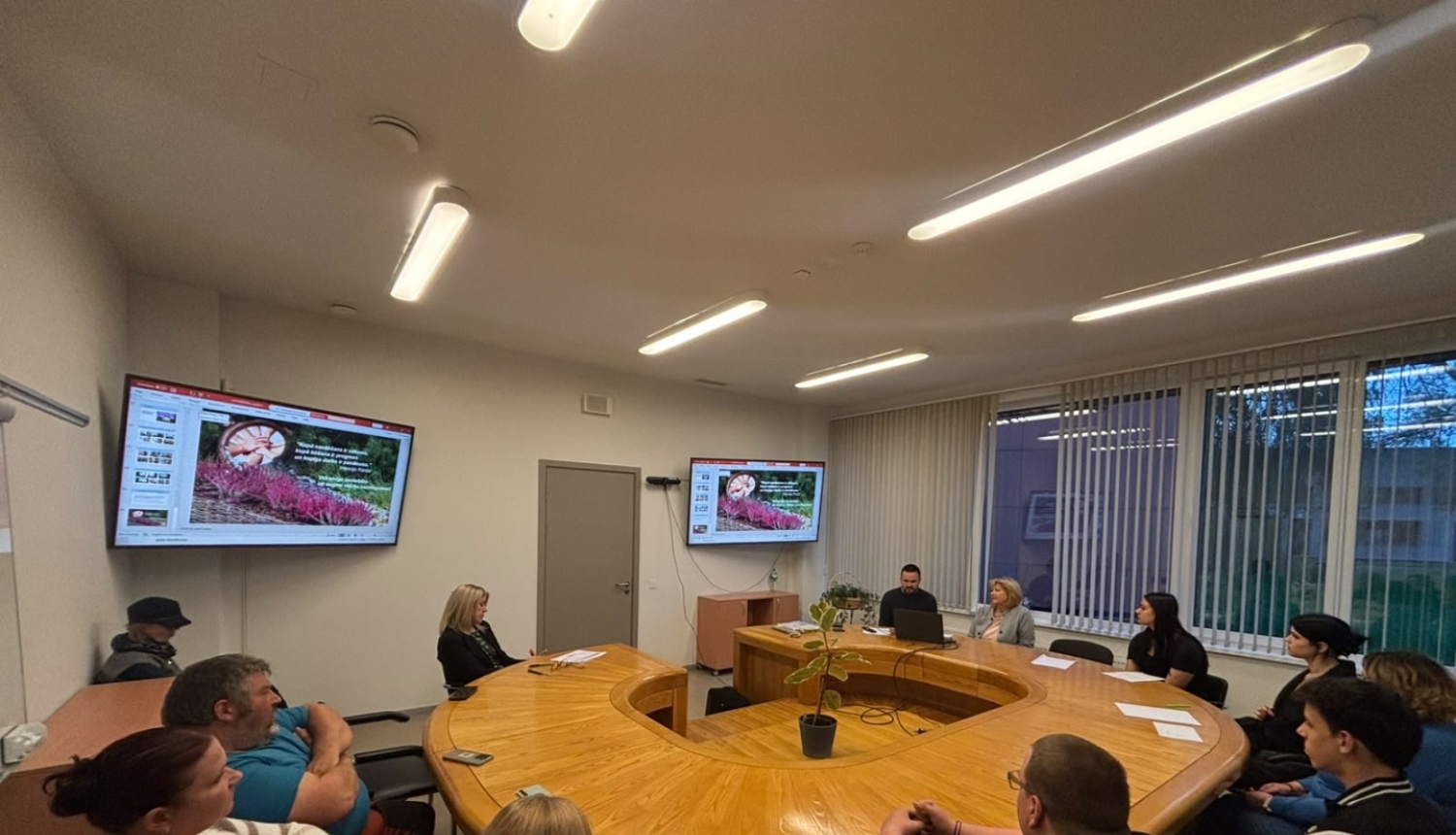 Cilvēki skolotāju istabā sēž pie galda